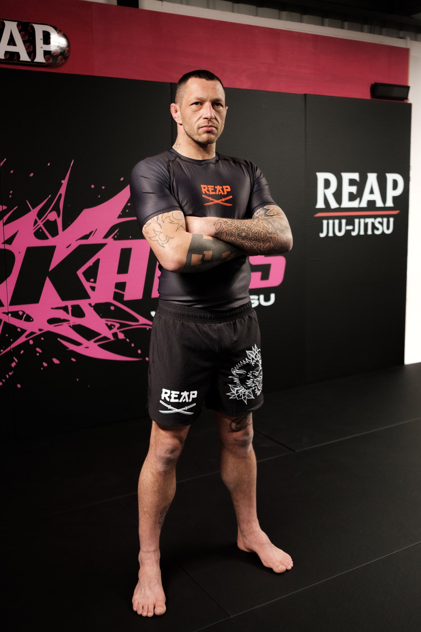 Person wearing Reap Jiu-Jitsu gear standing in front of a branded wall.