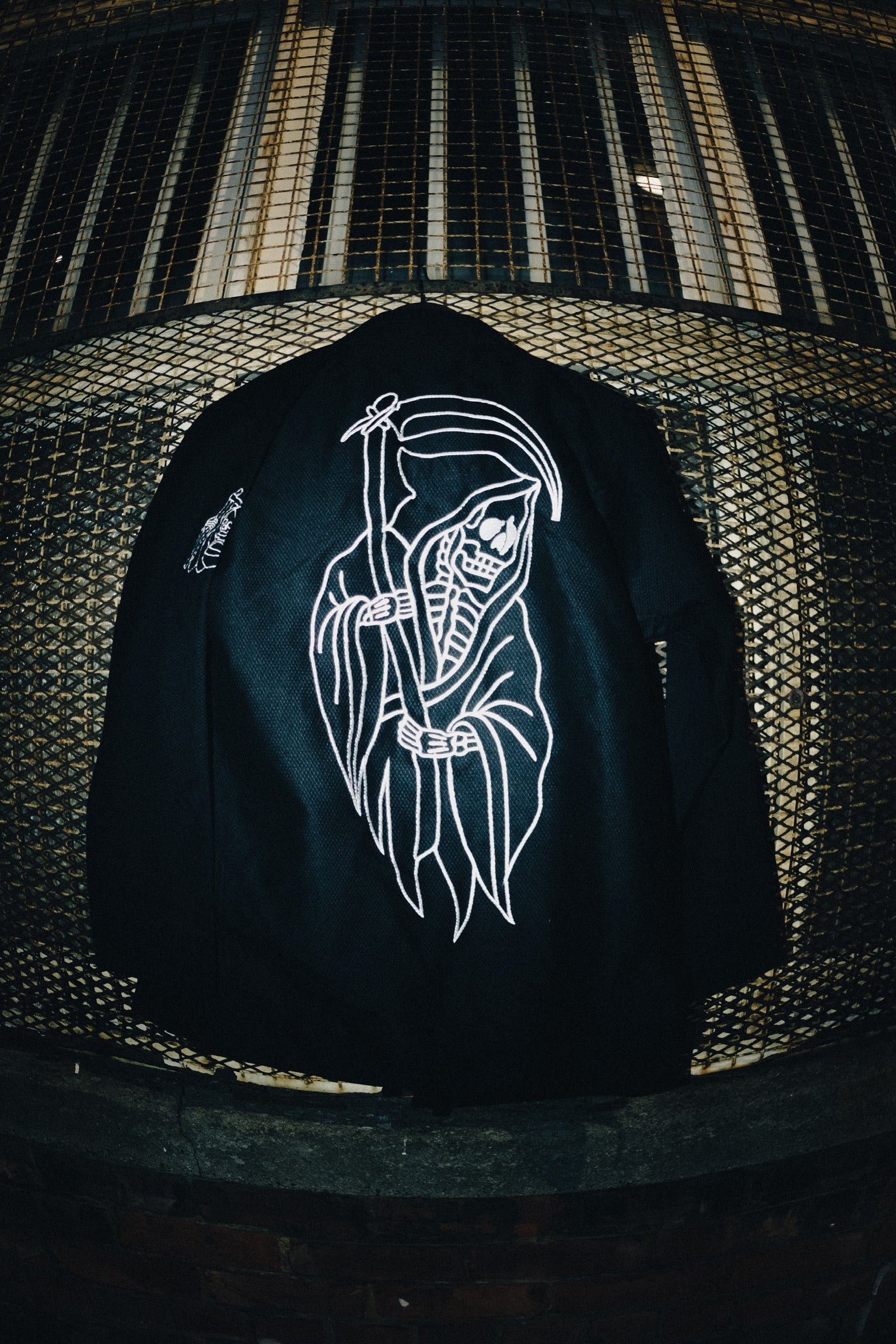 Black Gi with white graphic design of a skeleton holding a scythe against a textured black background.