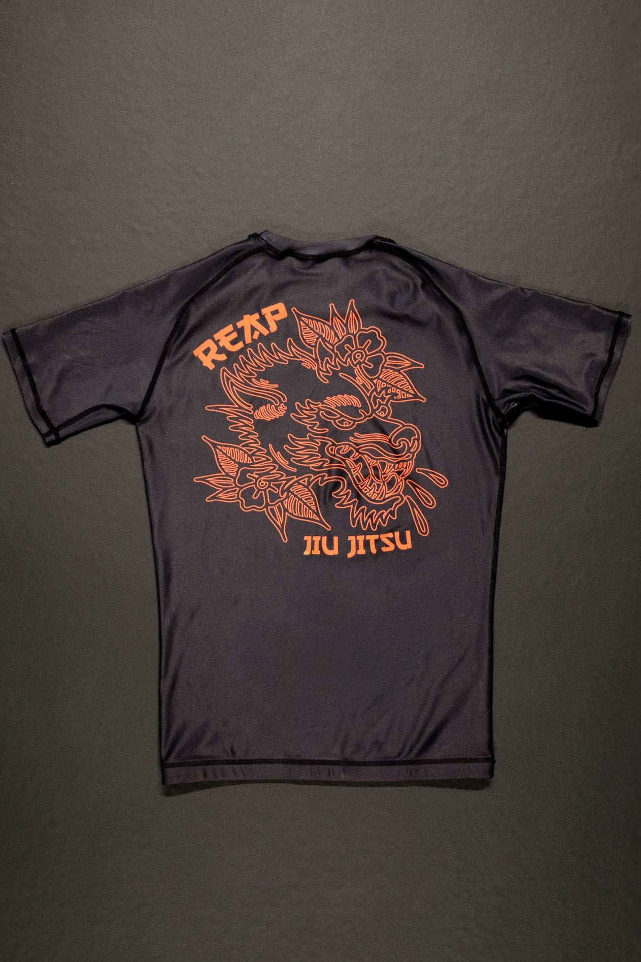 Black t-shirt with orange graphic design on a dark gray background
