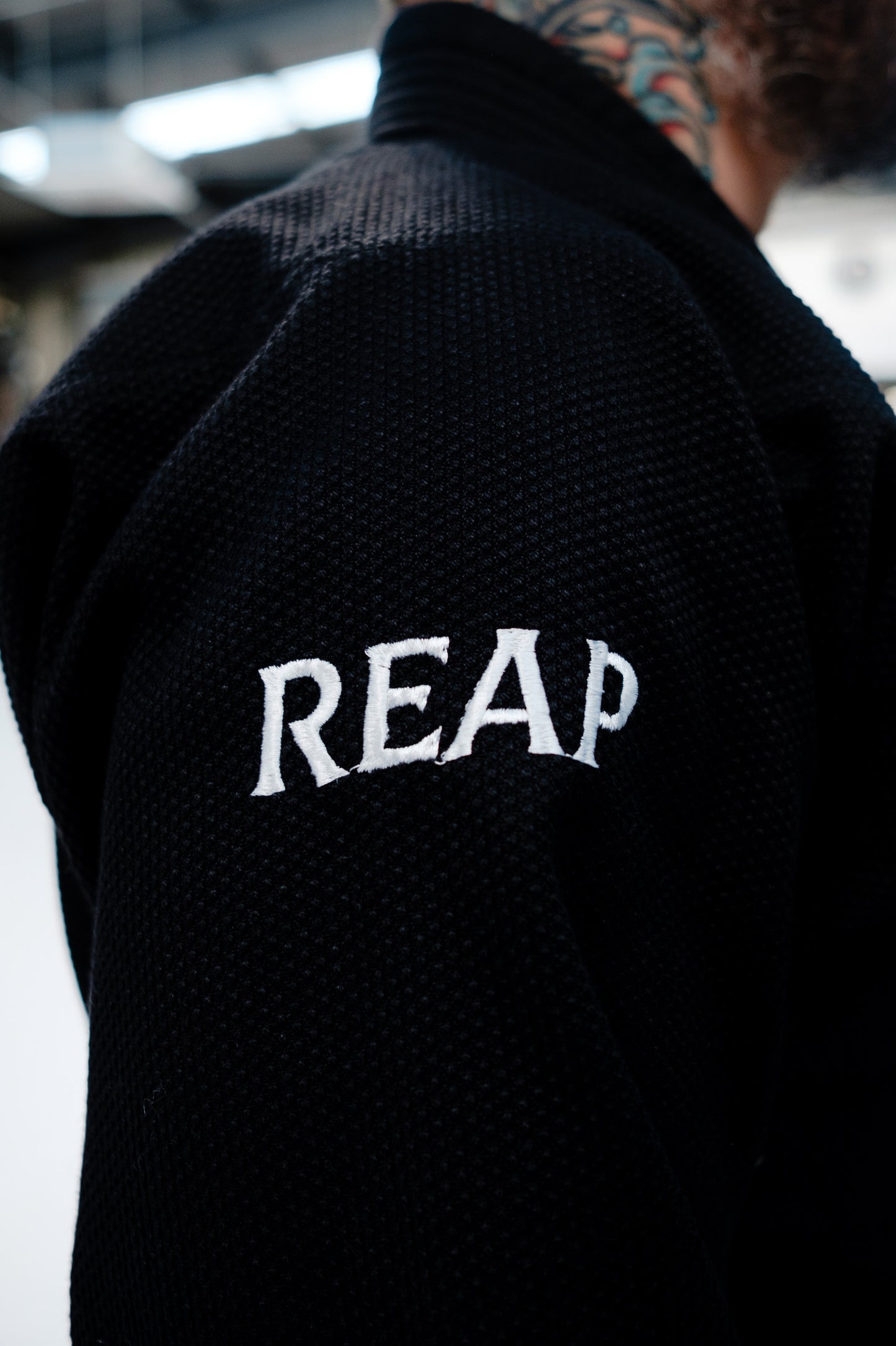 Black jacket with 'REAP' text on the back, blurred background