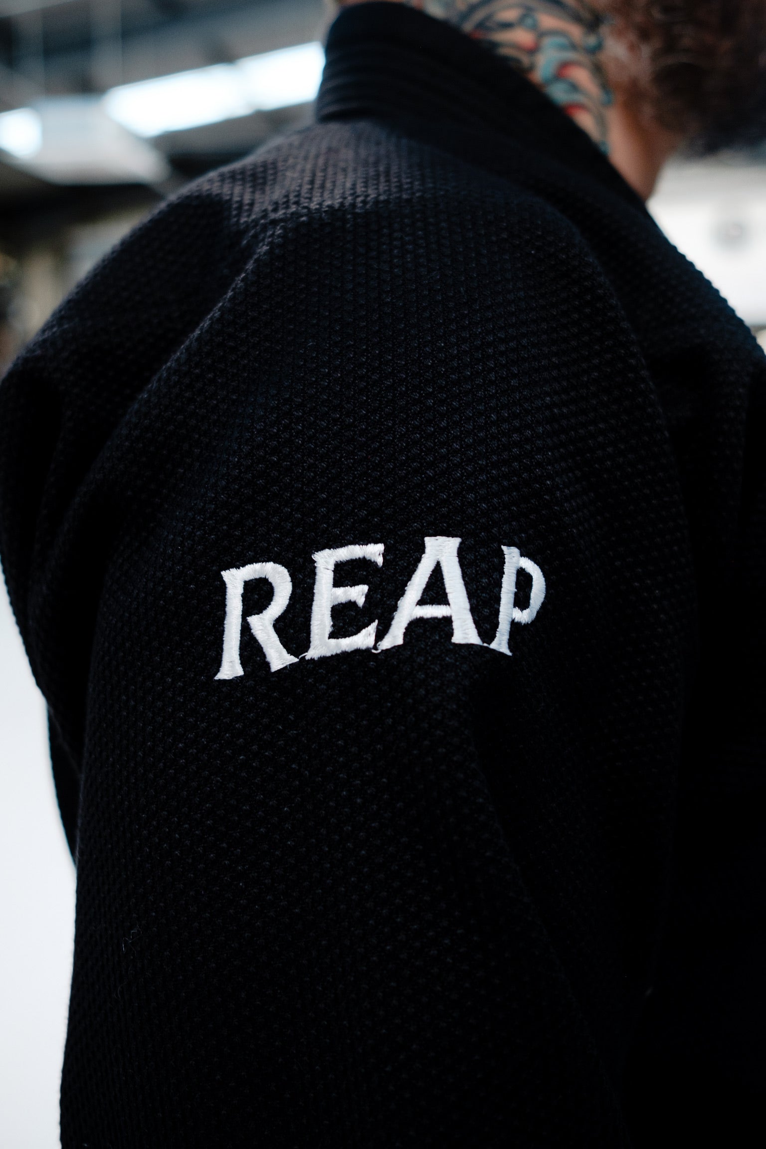 Black jacket with 'REAP' text on the back, blurred background