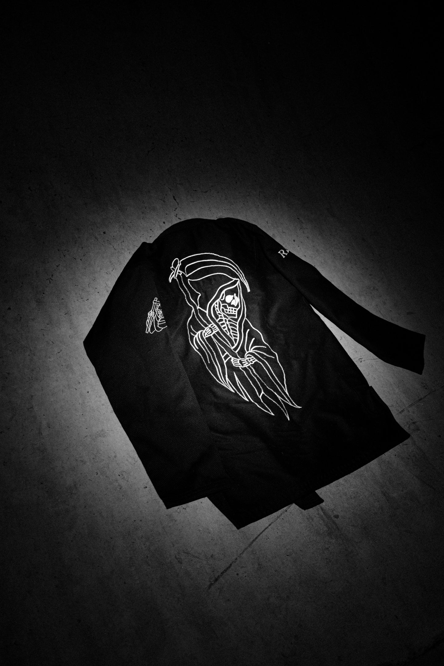 Black Gi jacket with white graphic design on a dark background