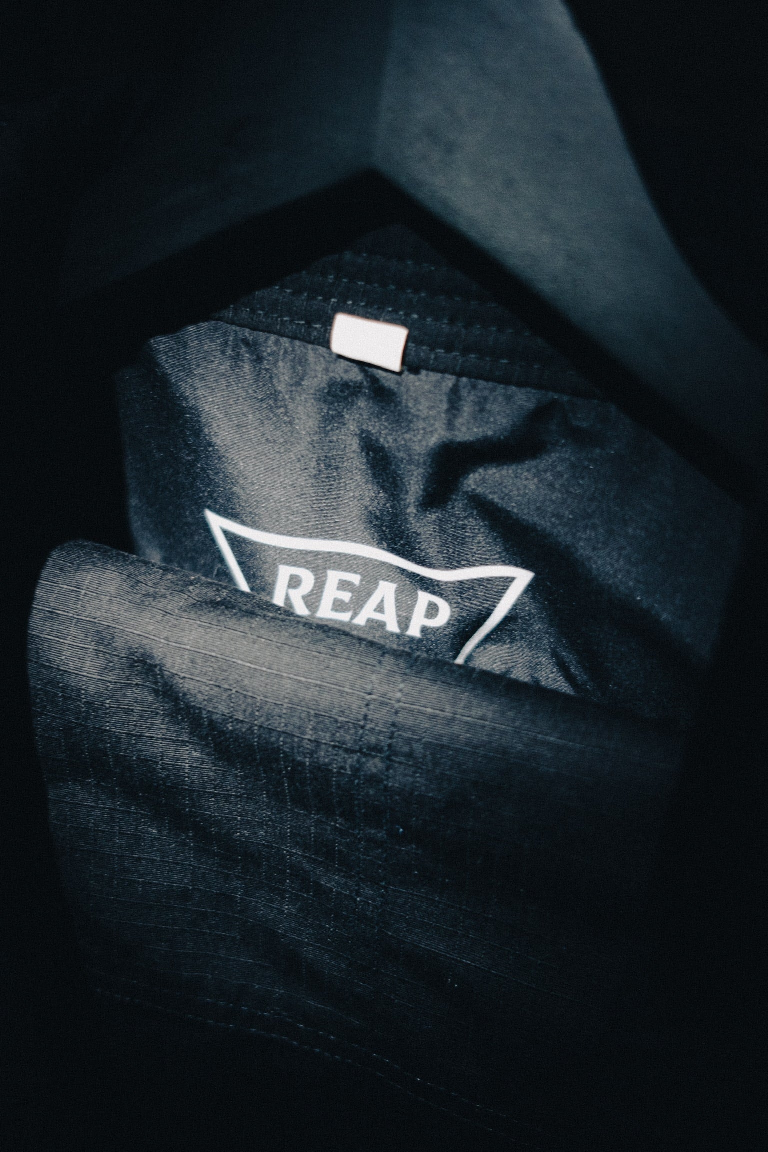 Dark fabric with 'REAP' logo on a black background