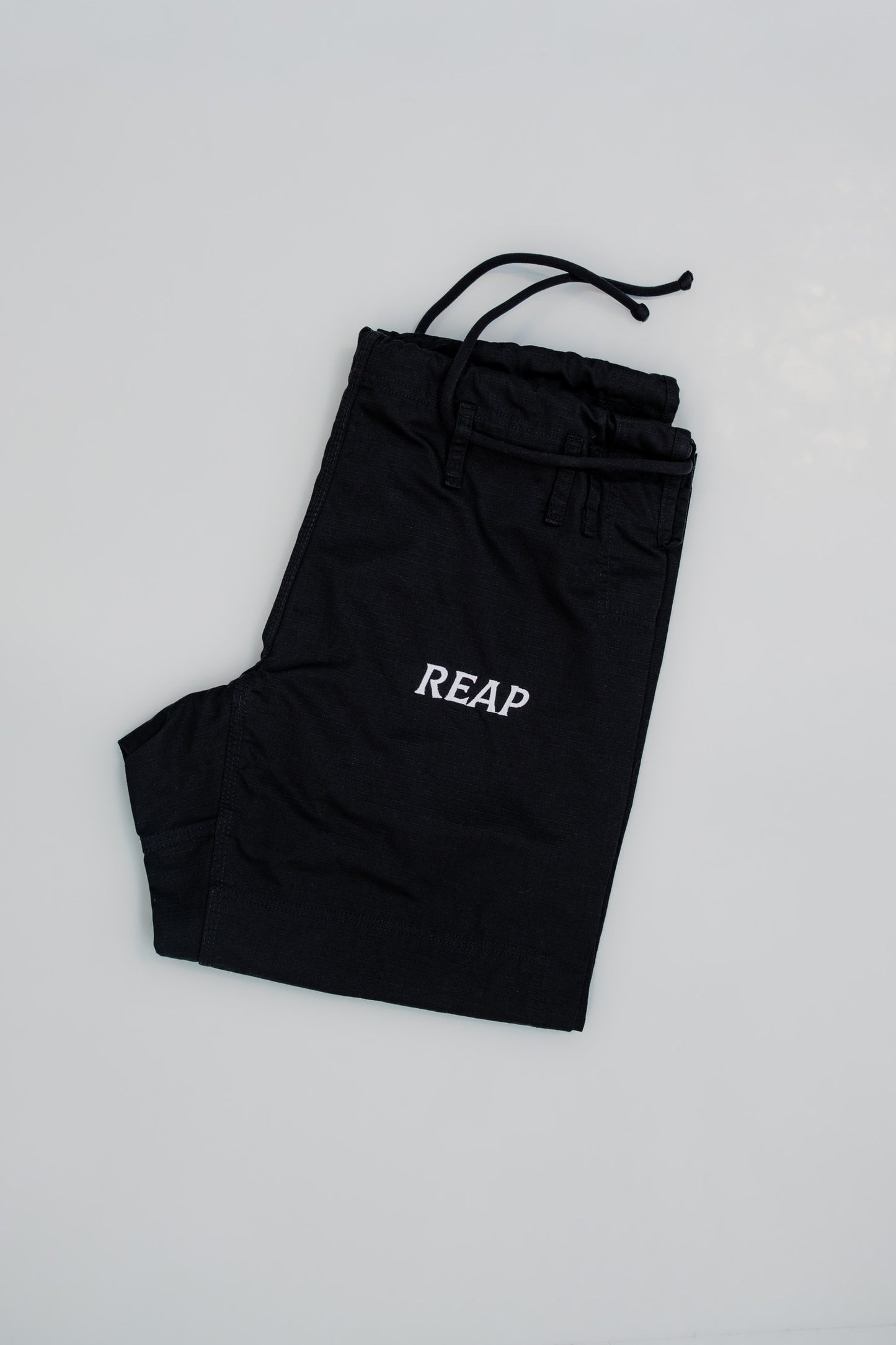 Black pants with 'REAP' text on a light gray background