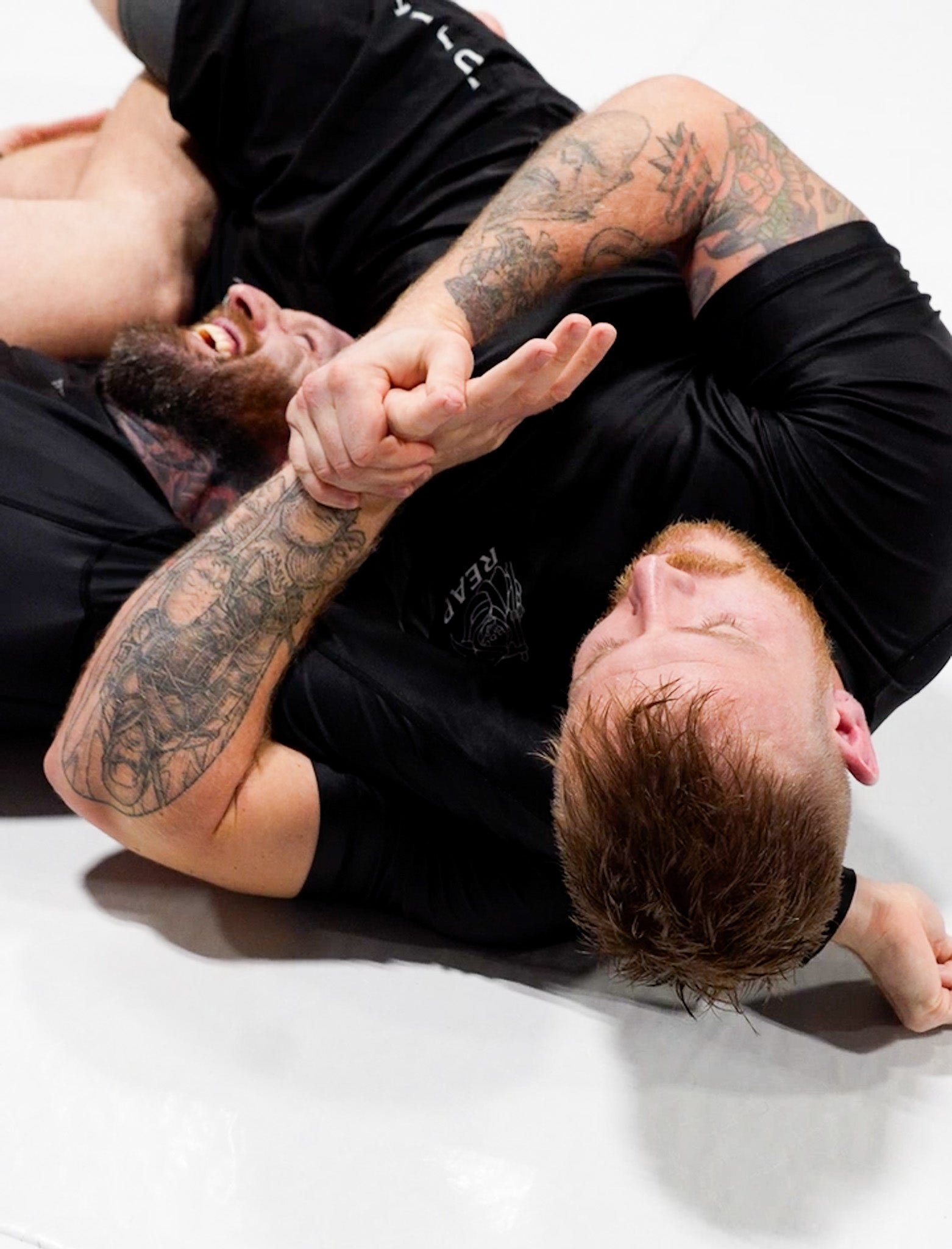 Two men in a grappling position on a white background