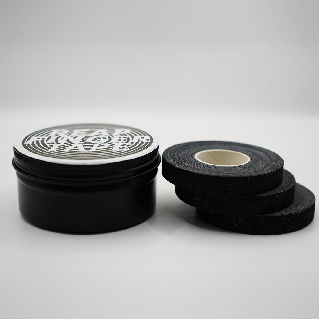 A stack of 3 rolls of jiu jitsu finger tape next to a back tin